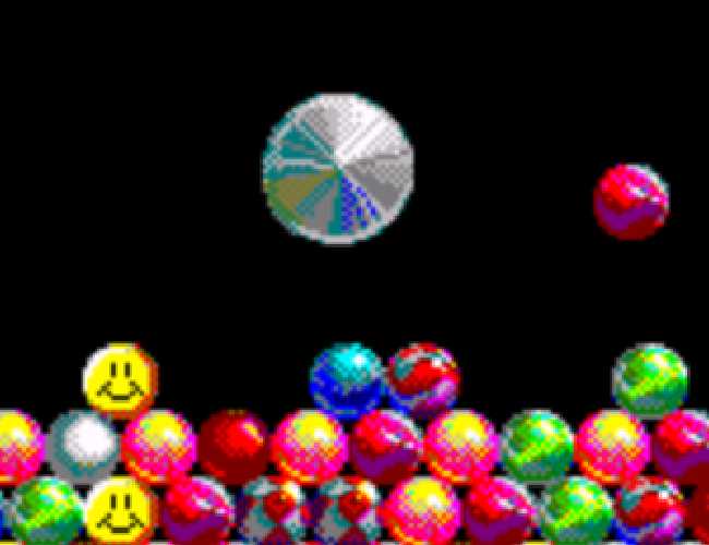A pile of small colorful marbles with a steel-colored pin above. A red marble is currently in the air, falling into the pile.